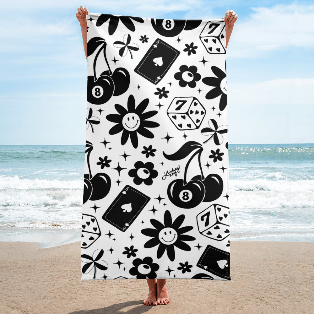 Retro beach towel with hand-illustrated pattern of cherries, smiley flowers, lucky dice, hearts, and stars, perfect for summer. In black and white.